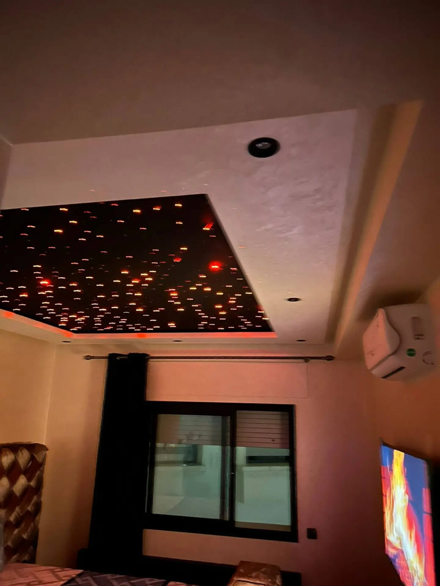 chambre-luxe-plafond-etoile-fibre-optique-domotique Chambre à coucher moderne avec faux plafond design intégrant un ciel étoilé en fibre optique rouge et climatisation réversible.