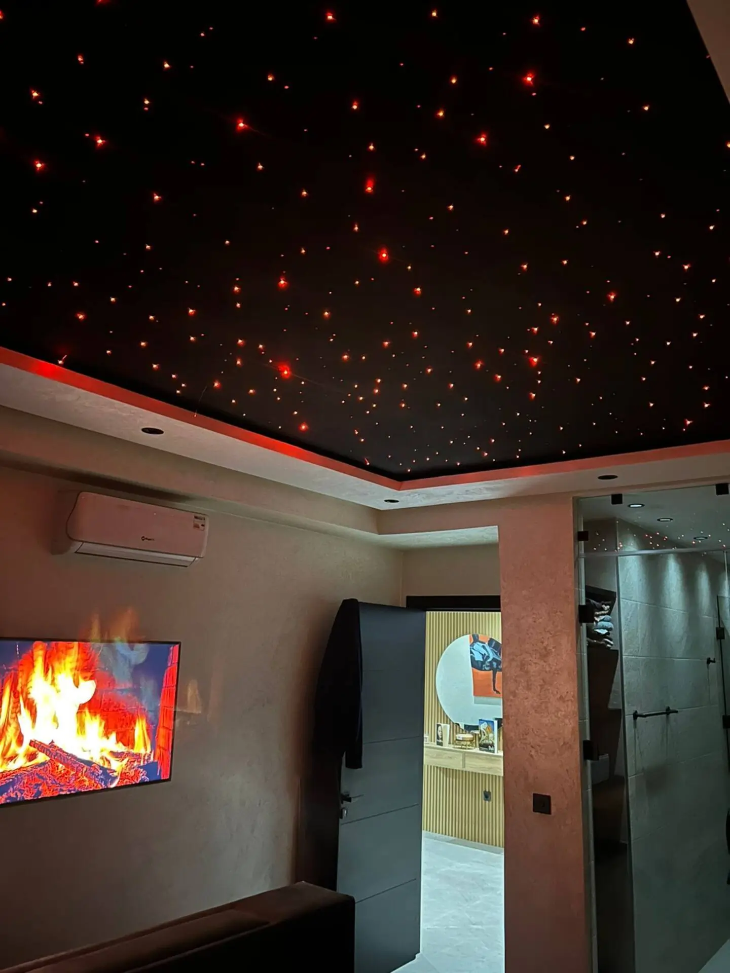 chambre-luxe-plafond-etoile-fibre-optique Design d'intérieur moderne avec plafond étoilé en fibre optique rouge, cheminée murale et finitions de luxe dans une suite parentale.