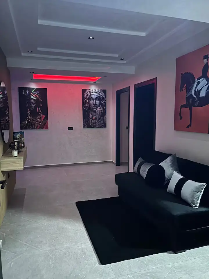 console-suspendue-bois-miroir-rond-design-entree Entrée moderne avec mur en tasseaux de bois, console flottante en chêne clair, miroir circulaire et éclairage d'ambiance LED rouge.