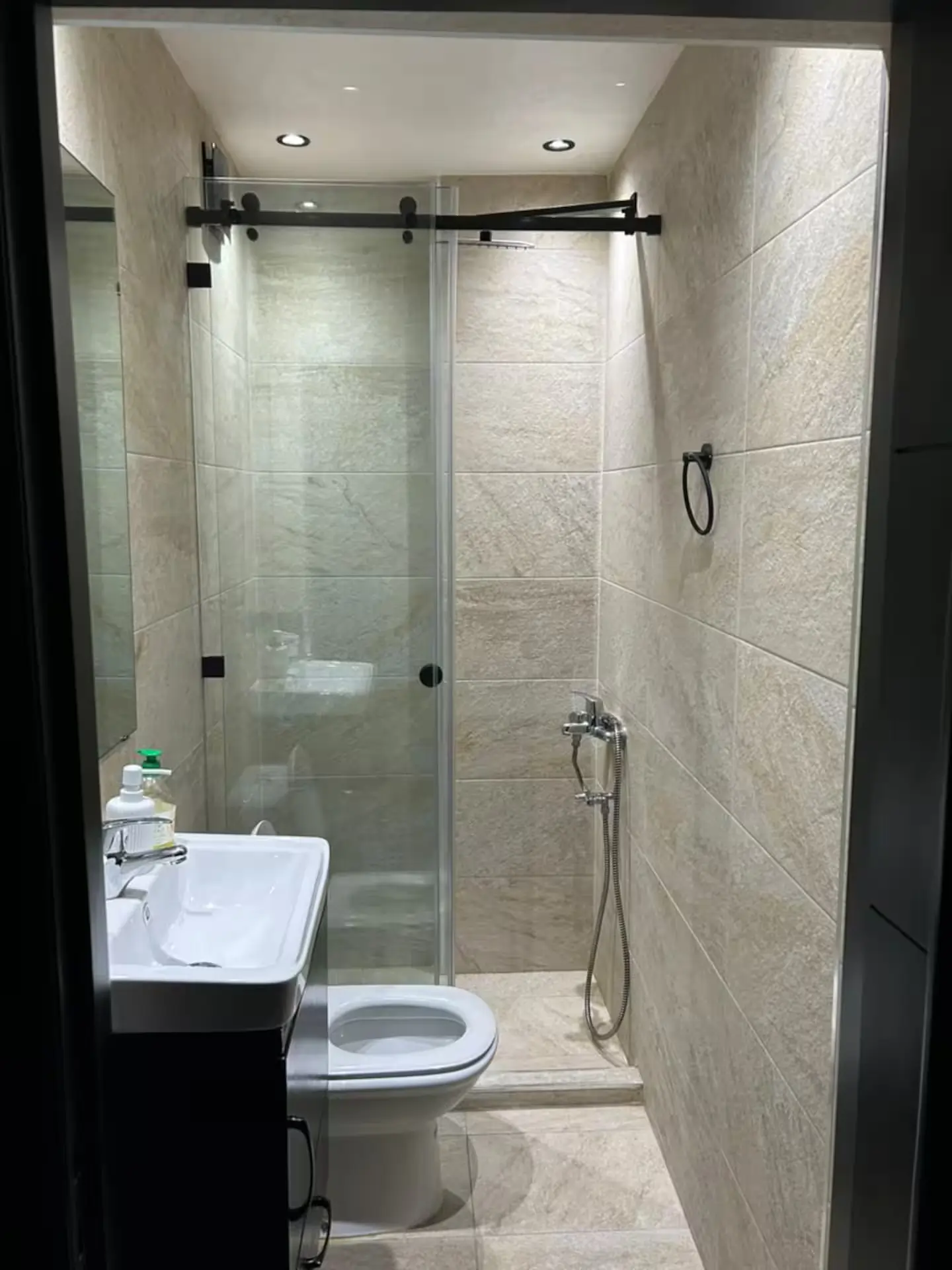 salle-de-bain-moderne-douche-italienne-marbre Petite salle de bain moderne avec douche à l'italienne vitrée, carrelage effet pierre naturelle beige et meuble vasque contemporain.